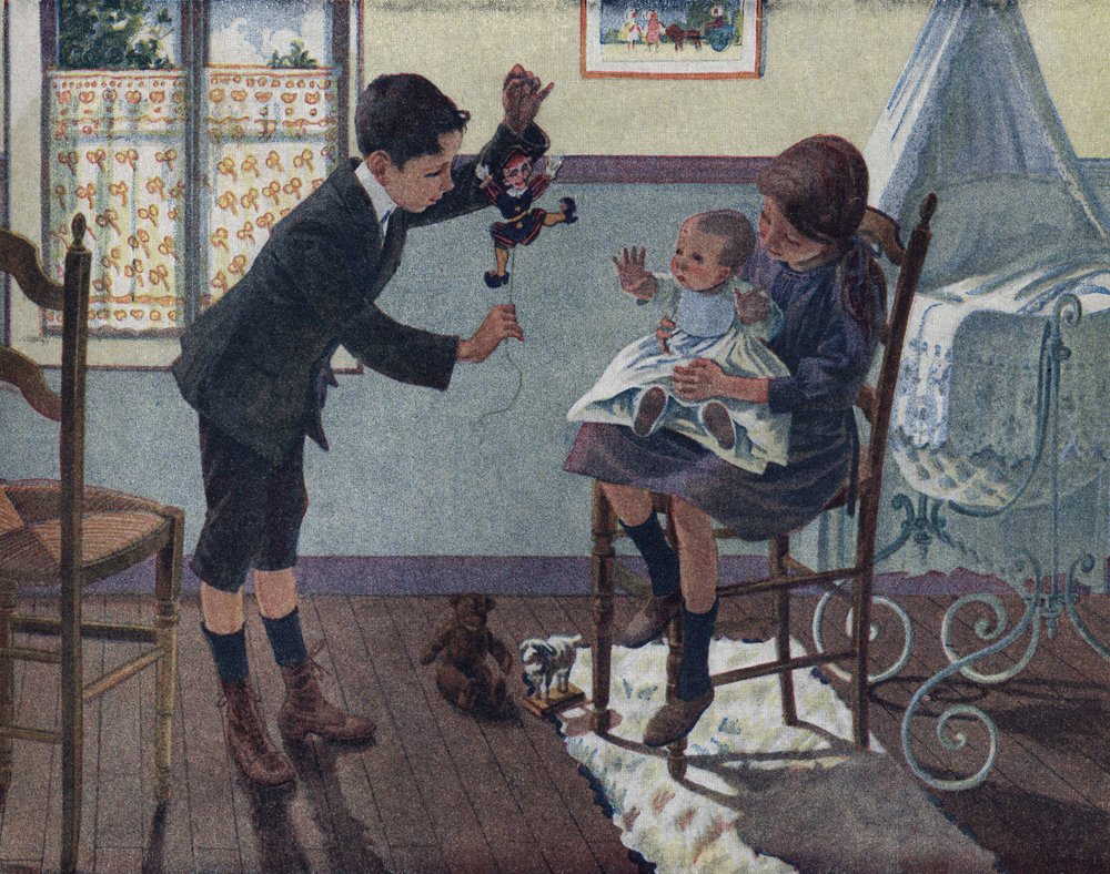 La educación del hermanito: en una habitación, un bebé sentado en el regazo de su hermana mayor mira la marioneta que su hermano despierta. Ilustración de Robert Salles (1871-1929) en “Yo sé Leer”. de Robert Salles