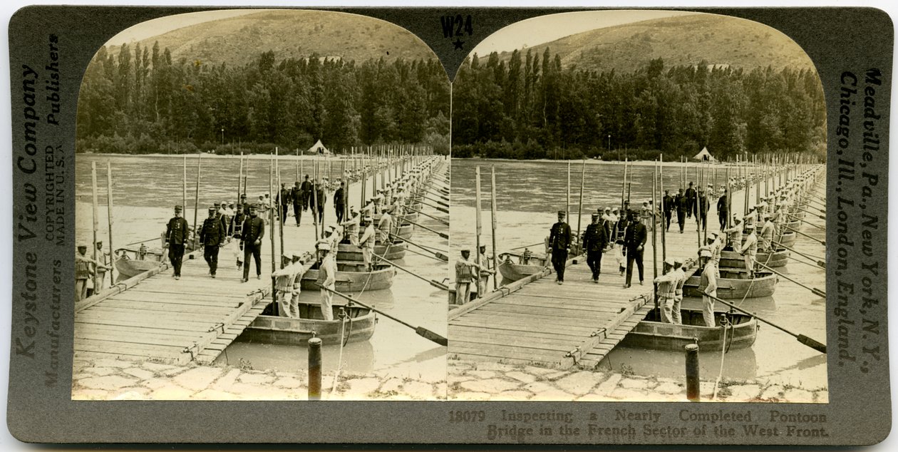 Horizontal, tarjeta estereoscópica sepia que muestra a oficiales uniformados cruzando un puente de pontones con hombres de pie en los pontones a ambos lados del puente. Número de estereografía de Keystone 18079 de Keystone View Company