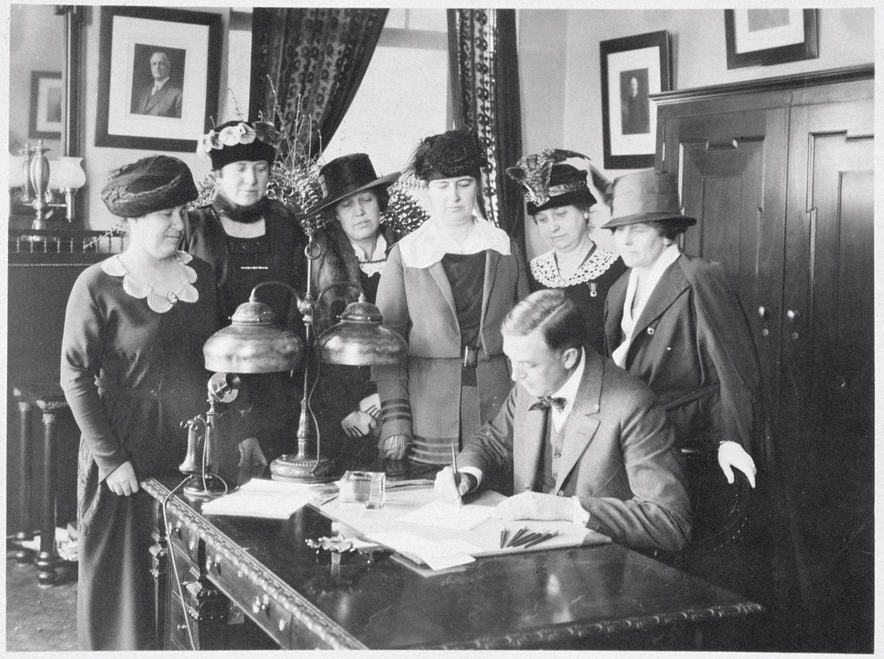 Gobernador Carl Elias Milliken firmando la Ley de Sufragio mientras seis mujeres observan, 1917 de American Photographer