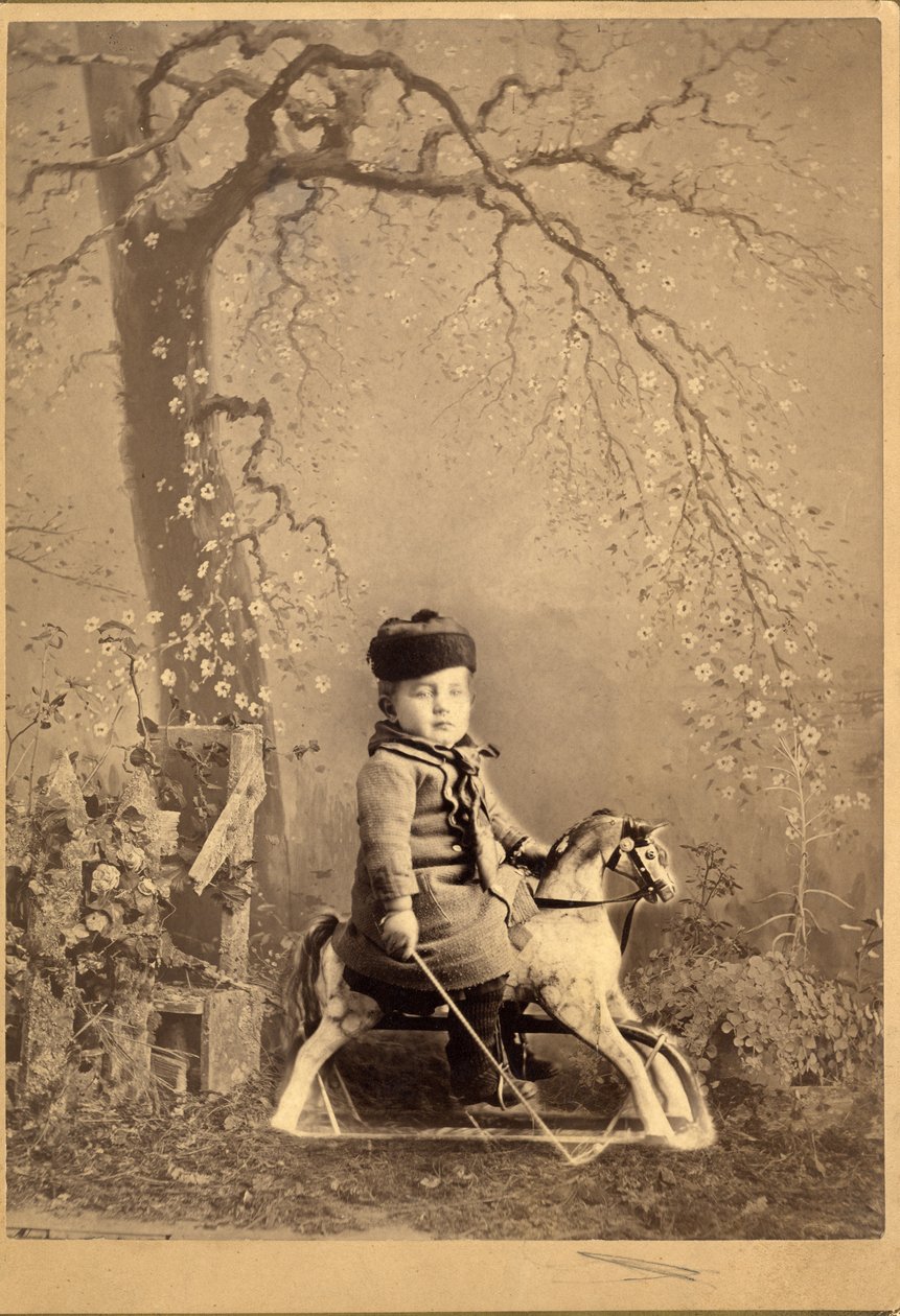 Niño sentado en un caballo de juguete con gran telón de fondo pintado, 1880s de American Photographer