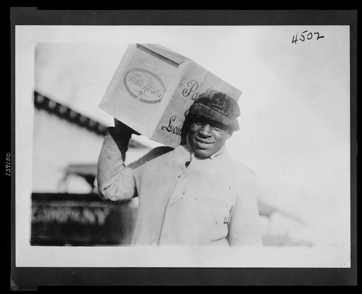 Hombre afroamericano cargando una caja de whisky 