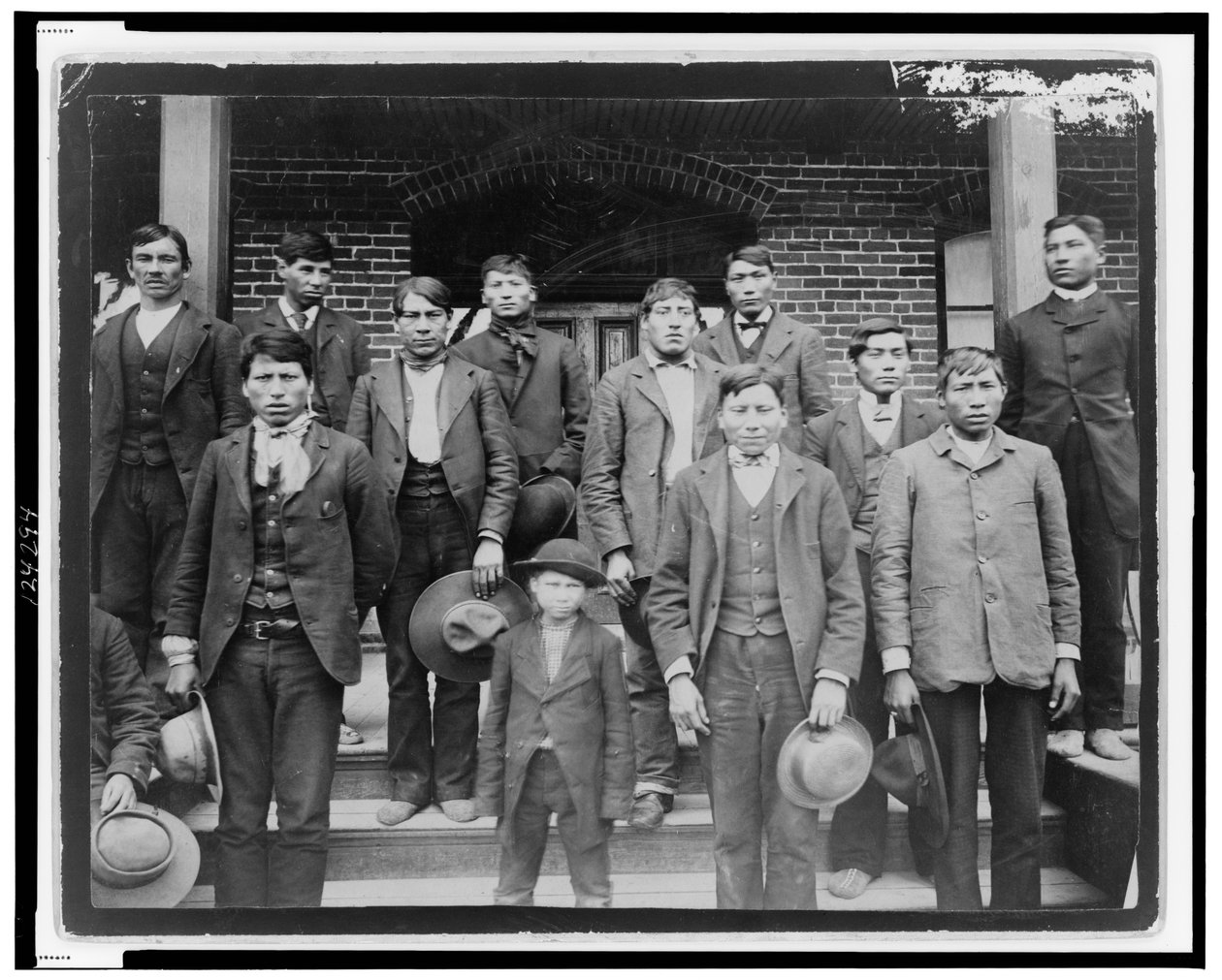 Hombres nativos americanos y un niño posando fuera de la Escuela India de Carlisle, Pensilvania, c.1890 de American Photographer