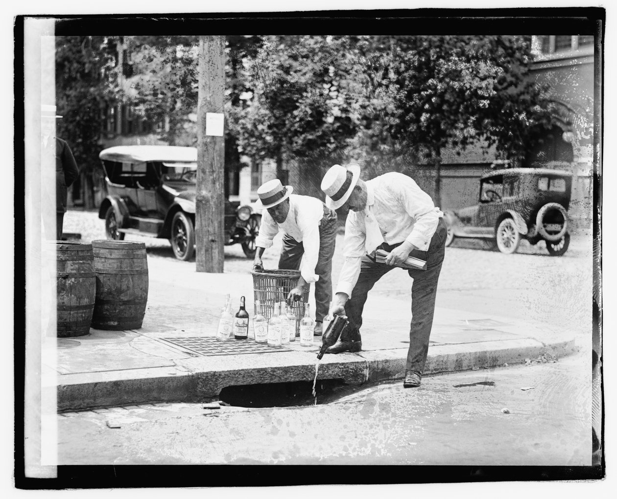 Dos hombres vertiendo licor en una alcantarilla, 8 de julio de 1921 de American Photographer