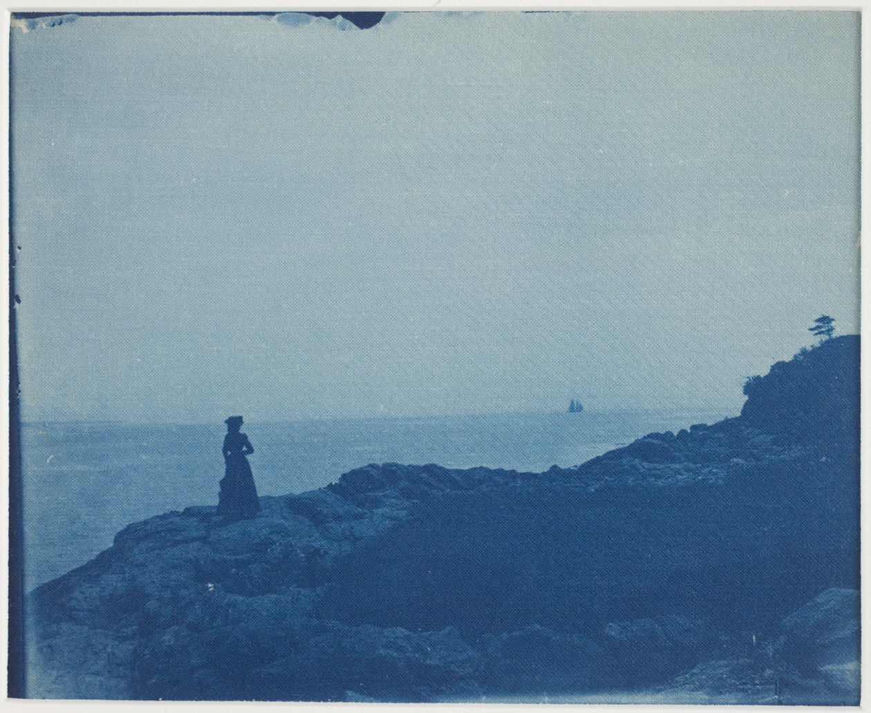 Mujer observando goleta desde un promontorio rocoso de American Photographer