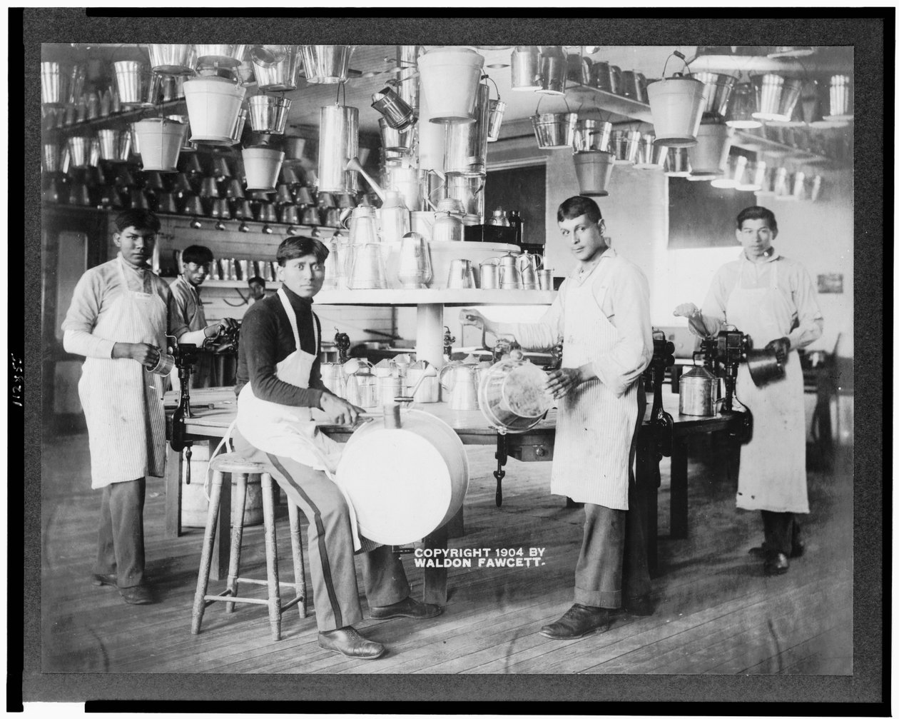 Jóvenes nativos americanos en taller de metalurgia con cubos, tinas, regaderas y otros artículos de metal, Escuela India de Carlisle, Pensilvania, c.1904 (foto en b/n) de American Photographer