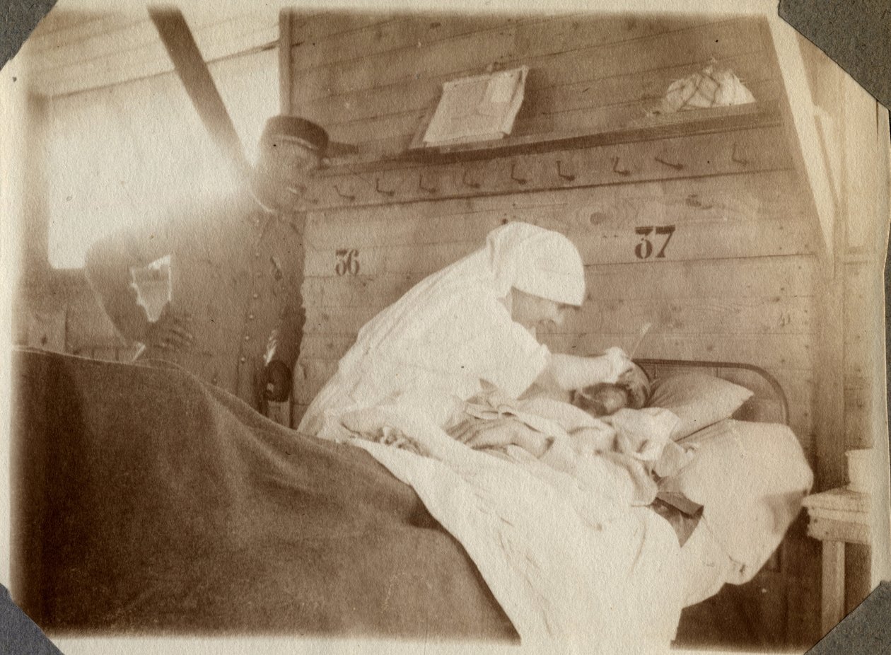 Primera Guerra Mundial 1914-1918: enfermera en bata afeitando a un soldado (herido de guerra francés en una cama), en Couville, Mancha, Baja Normandía, Francia. Fotografía anónima julio 1917. Colección privada, Stella. de Anonymous Anonymous