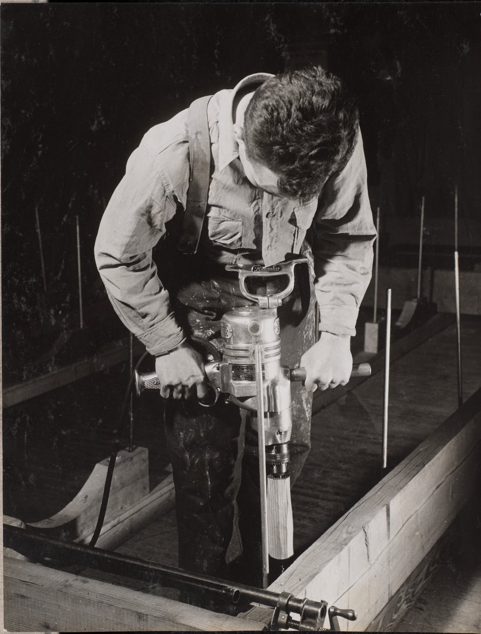 [Un hombre utiliza una máquina manual para trabajar con un trozo de madera]. de Arnold Eagle