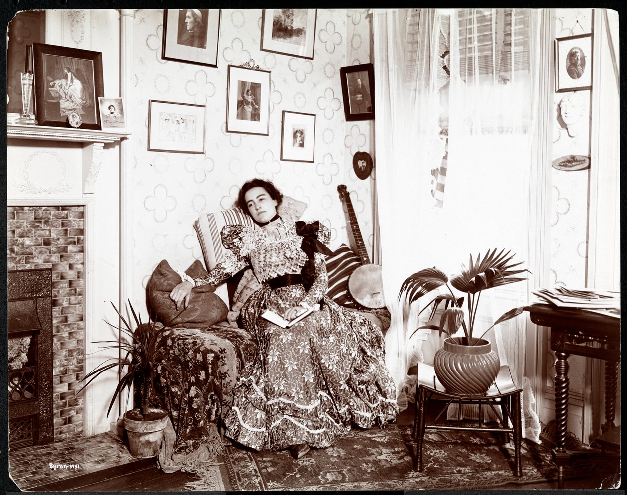 Una mujer descansando en una silla, leyendo un libro, 1896-98 de Byron Company
