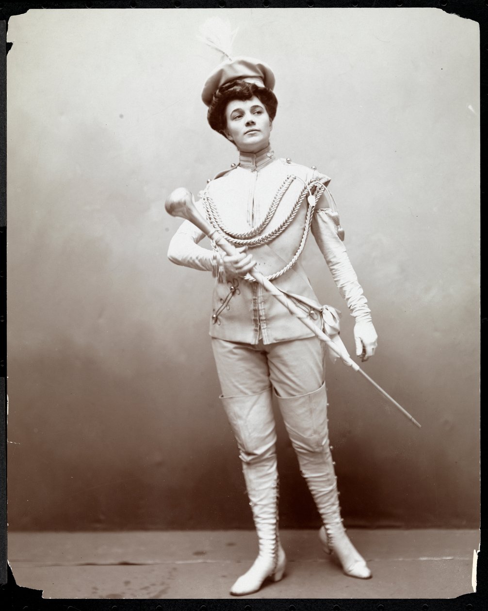 Una mujer modelando un uniforme de banda, sosteniendo una batuta, c.1898 de Byron Company