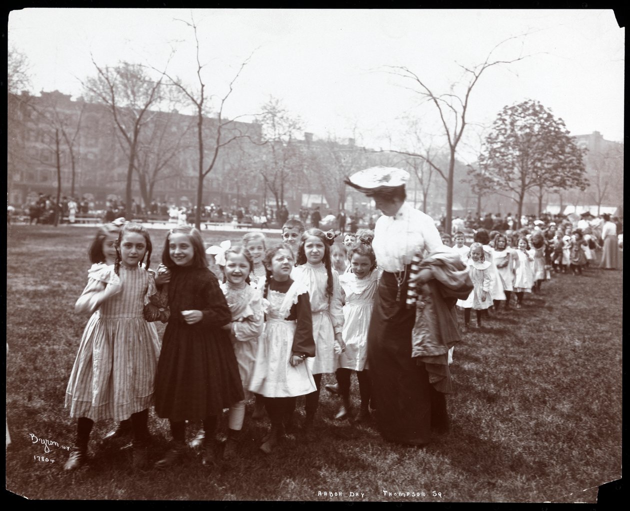 Niños en una larga fila siendo guiados por una mujer en el Día del Árbol en Tompkins Square Park, Nueva York, 1904 de Byron Company
