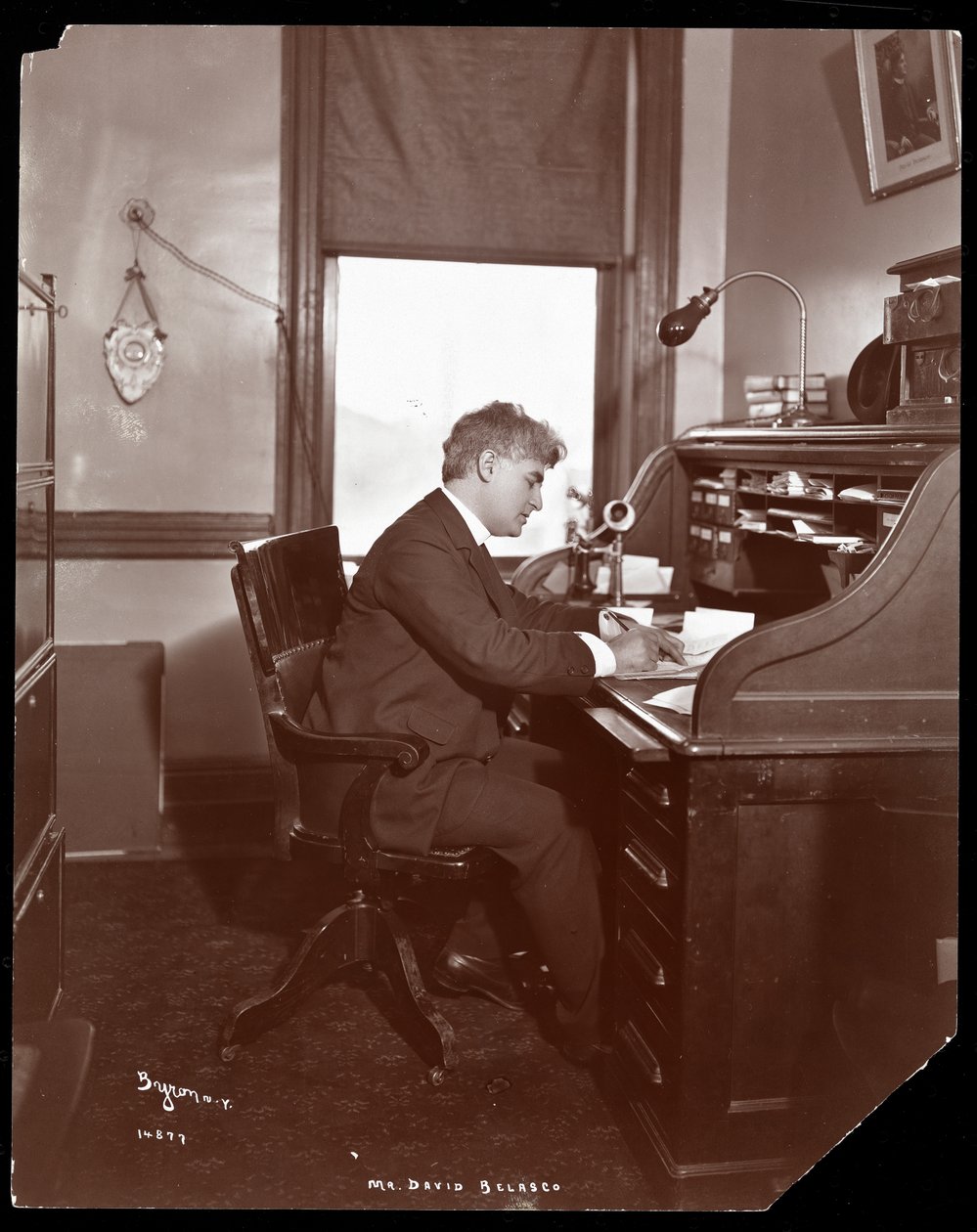 David Belasco escribiendo en un escritorio en las oficinas de su teatro, 1902 de Byron Company