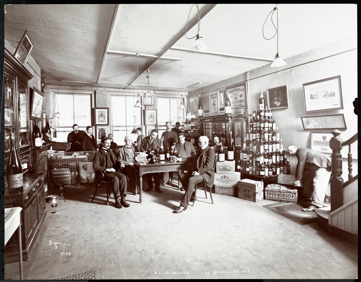 Grupo de hombres bebiendo vino en G.L. Nicholas, comerciantes de vino y licor, 43 Beaver Street, Nueva York (1895) de Byron Company
