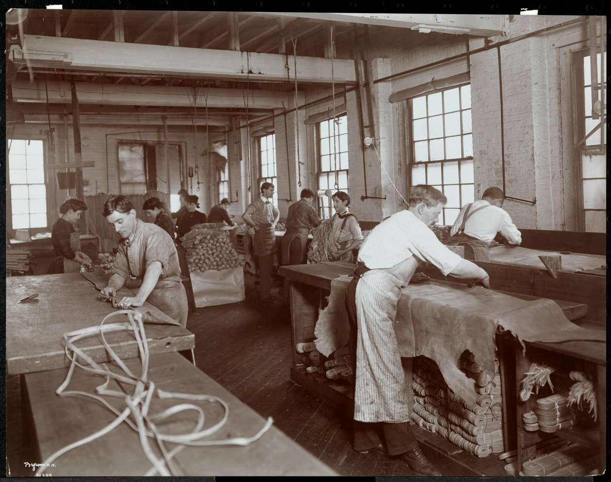 Vista interior de hombres y mujeres trabajando con cuero en la New York Leather Belting Co., Nueva York, 1906 de Byron Company