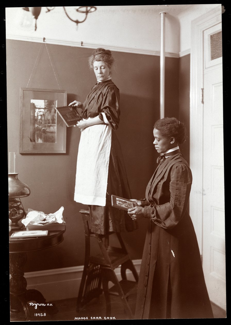 Madge Carr Cook colgando cuadros con su criada, c.1904 de Byron Company