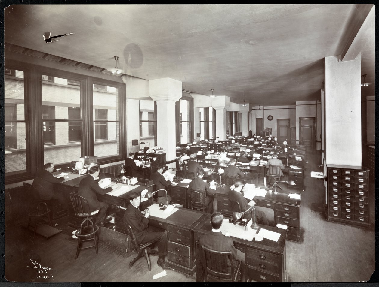 Hombres y una mujer trabajando en escritorios en una oficina de la Metropolitan Life Insurance Co. en la Calle 23 y la Avenida Madison, Nueva York, 1907 de Byron Company