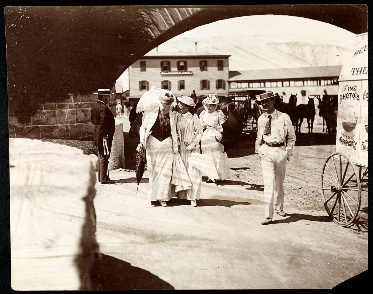 Tres mujeres y un hombre caminando en el muelle de Narragansett con el carrito del fotógrafo itinerante, Rhode Island, 1891 de Byron Company