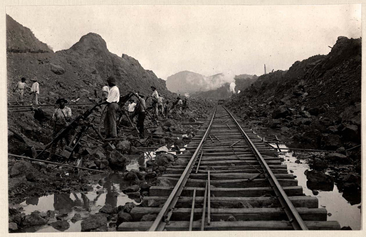 Vista de trabajadores cavando el Canal de Panamá con vías de tren a través de la zanja, 1912 o 1913 de Byron Company