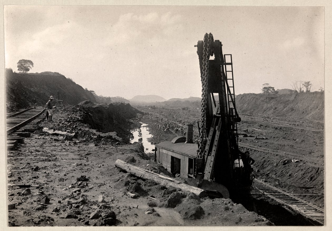 Vista de trabajadores excavando el Canal de Panamá con vías de tren a través de una zanja y algún tipo de máquina excavadora en primer plano, 1912 o 1913 de Byron Company