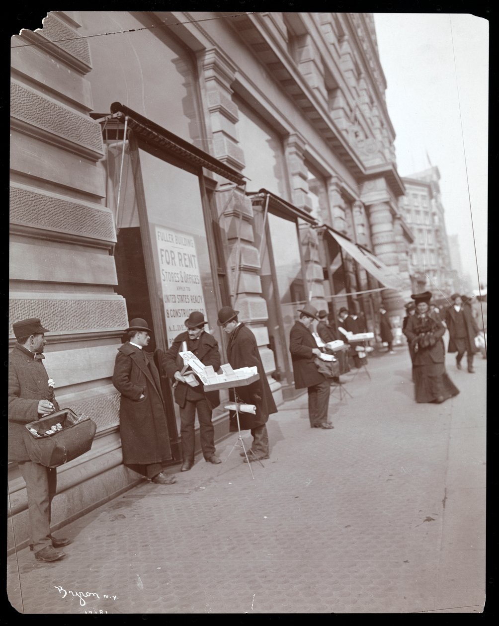 Vista de vendedores ambulantes vendiendo juguetes y otros artículos frente al Edificio Fuller o Flatiron en Broadway, 5ª Avenida y Calle 23, Nueva York, c.1895 de Byron Company