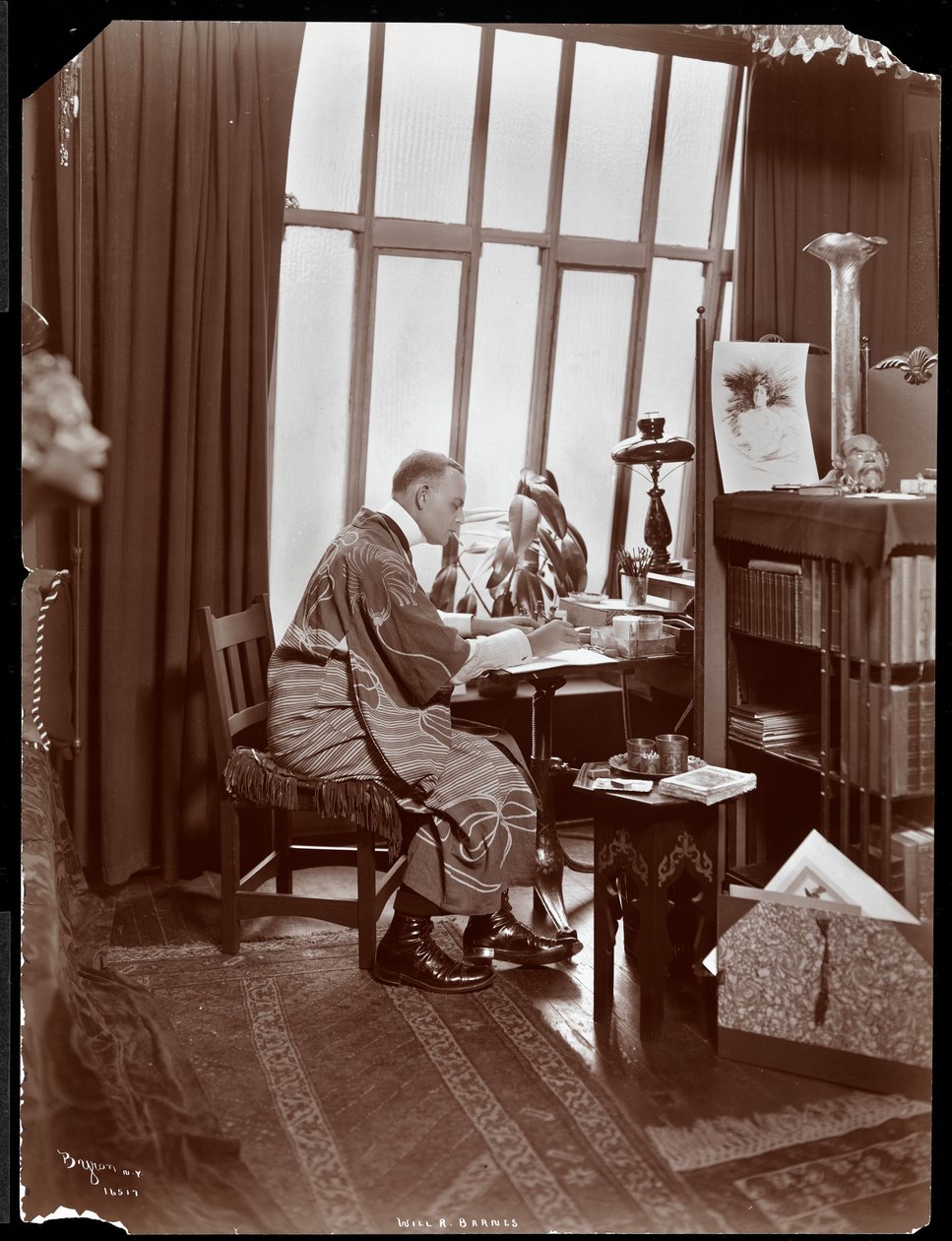 Will R. Barnes en una bata, sentado en su escritorio en su estudio, 1903 de Byron Company