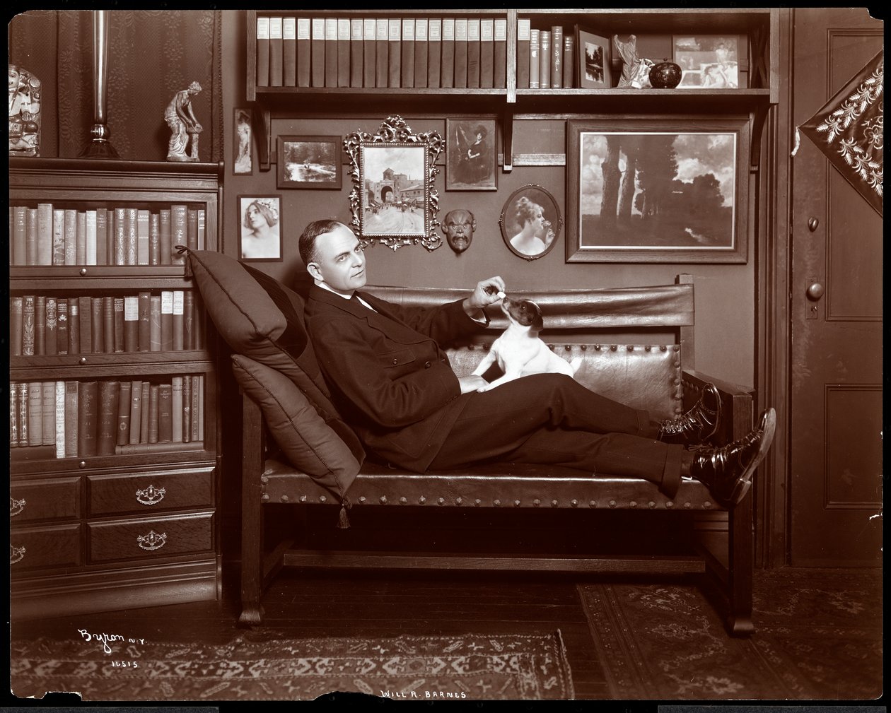 Will R. Barnes reclinado en un sofá con un perro en su estudio biblioteca, 1903 de Byron Company