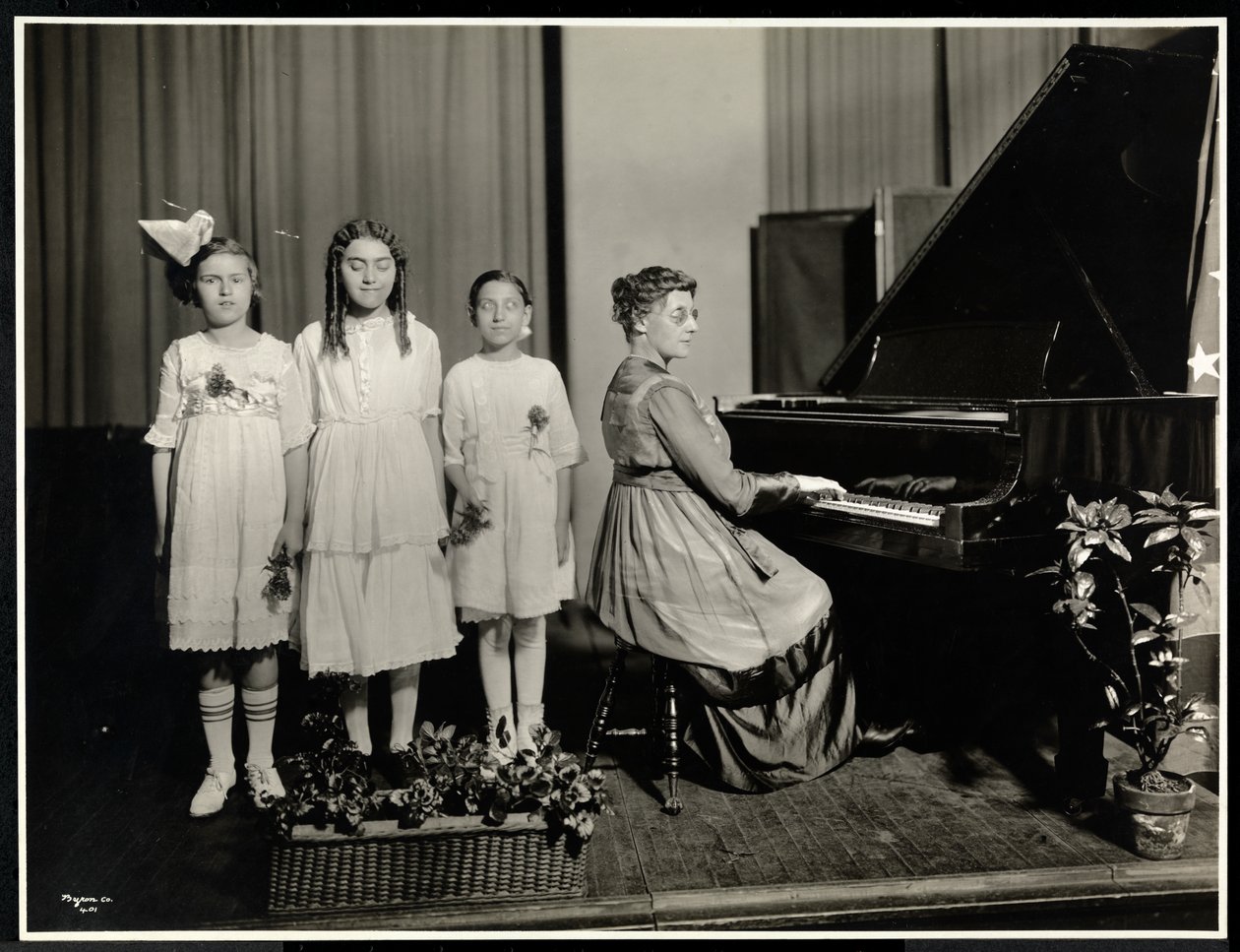 Mujer tocando el piano mientras tres niñas cantan en la Asociación para Ciegos de Nueva York, 111 East 59th Street, Nueva York, c.1917 de Byron Company