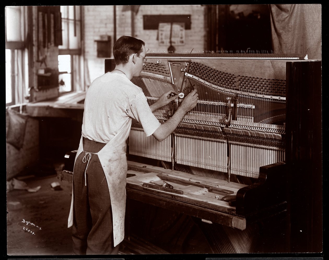 Hombre trabajando en la fábrica de pianos Hardman, Peck y Co., Nueva York, 1907 de Byron Company