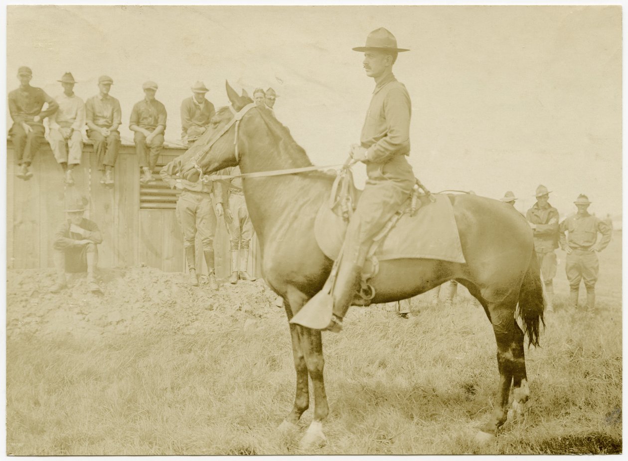 Soldados reunidos alrededor y observando a un soldado uniformado a caballo en un campo de hierba de Carl Michel