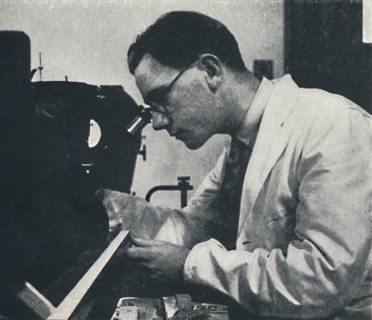 Investigador con microscopio probando la estructura de una aleación de aluminio de Cecil Beaton