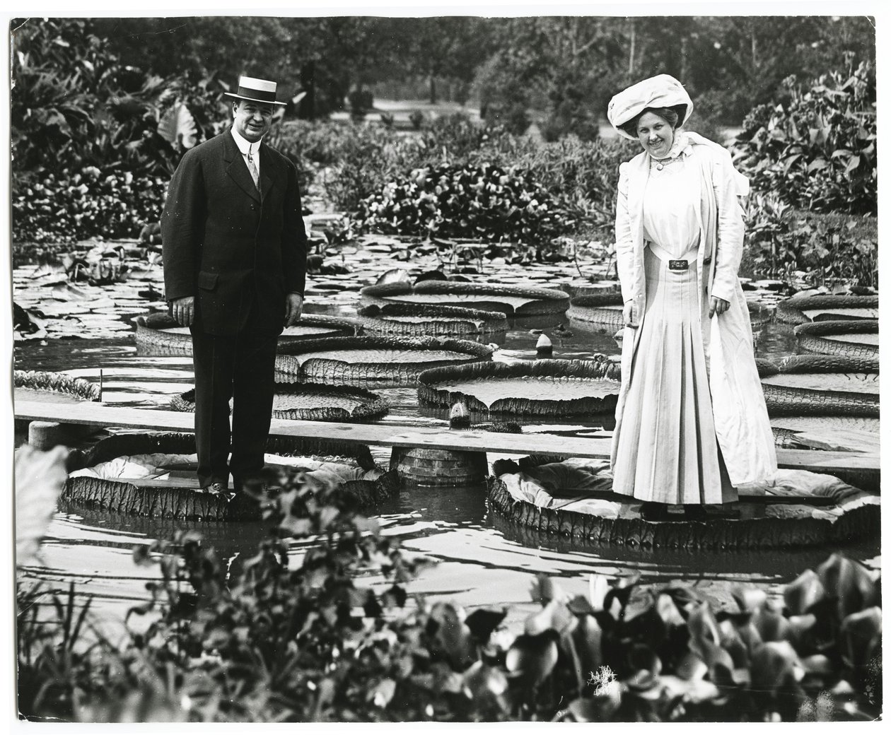Estanque de lirios en Tower Grove Park. Hombre y mujer de pie sobre hojas de lirio. de Charles Clement Holt