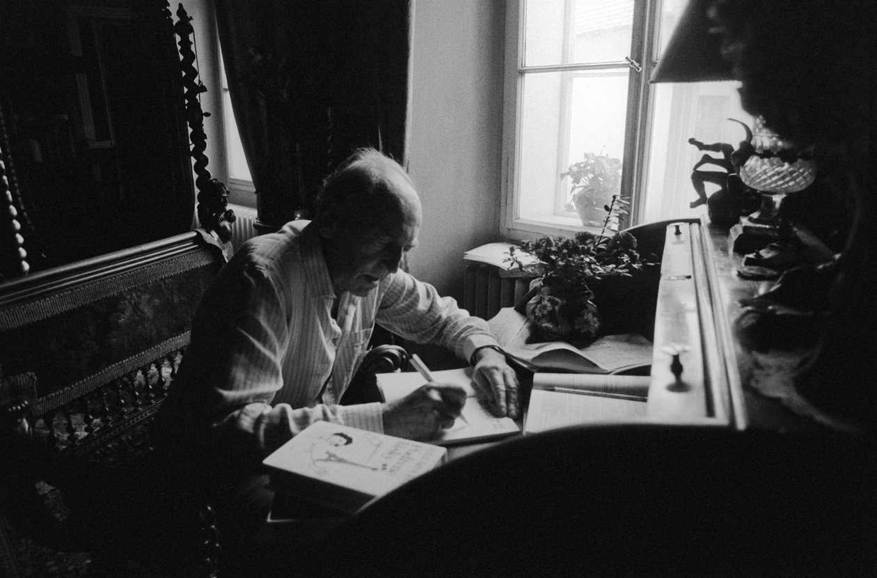 Jiri Mucha sentado en su escritorio en su casa en Hradcany, Praga de Czech Photographer