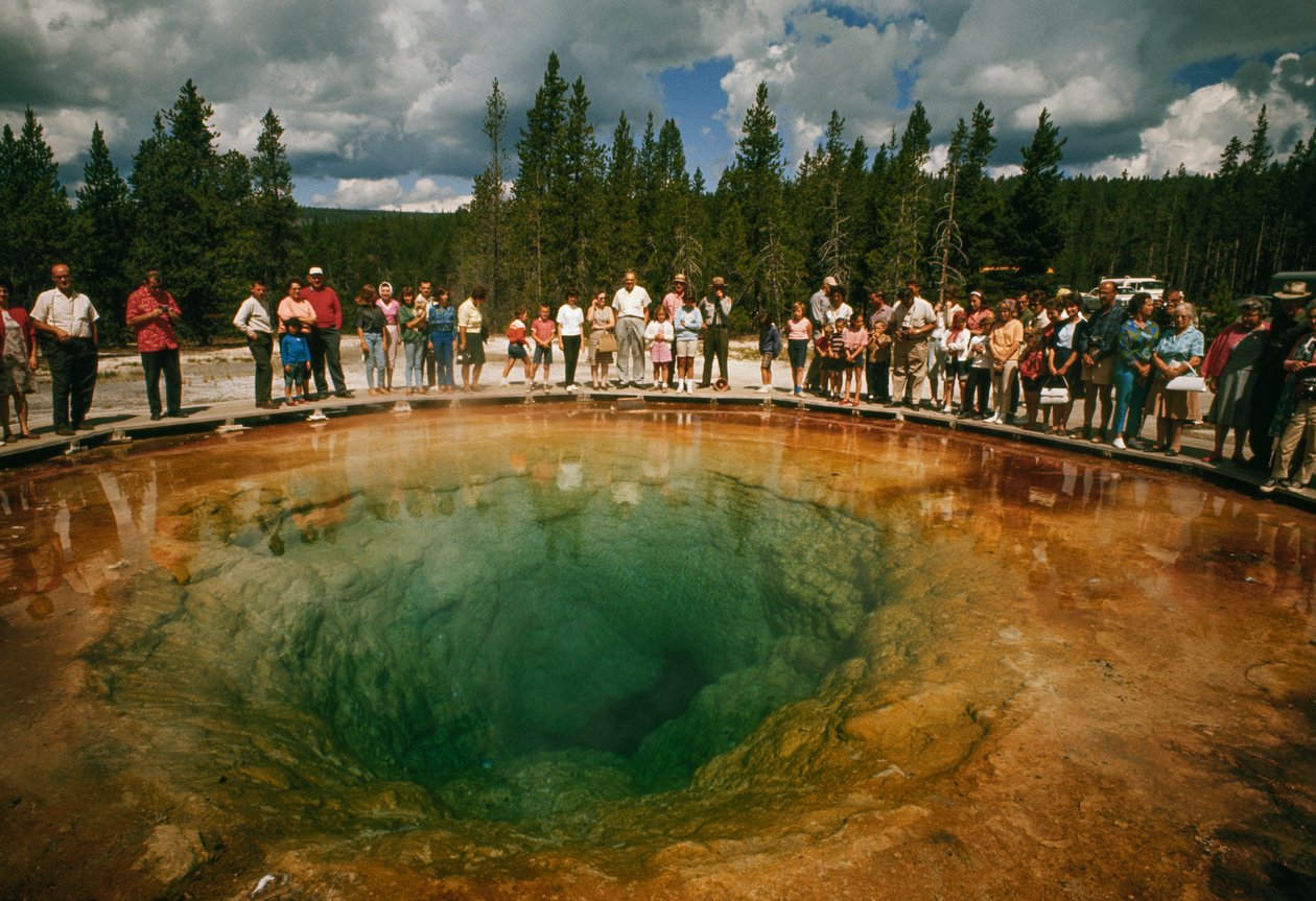 Visitantes del parque se reúnen en torno a una piscina termal verde azulada con forma de flor. Yellowstone Nati... de Dean Conger