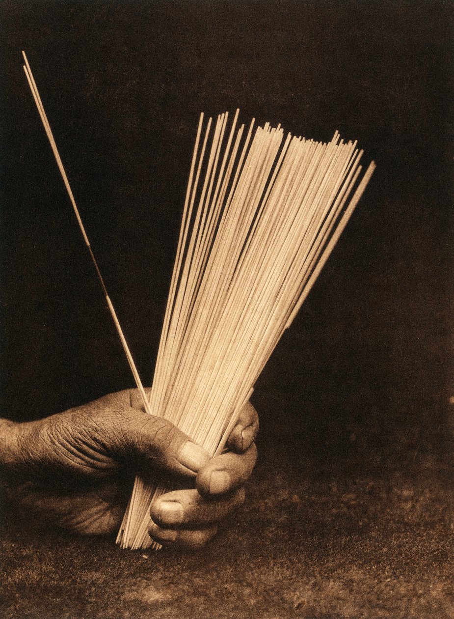 Primer plano de la mano de un indio de la tribu o pueblo Hupa sosteniendo unas varillas de adivinación. de Edward Sheriff Curtis