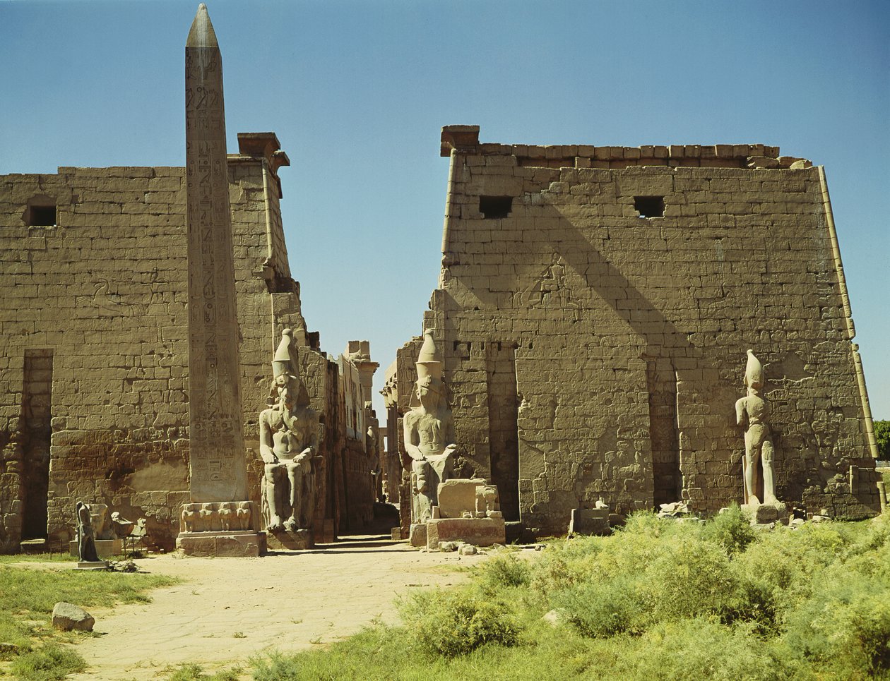 Fachada y Primer Pilón con dos estatuas sentadas de Ramsés II y el obelisco restante de Egyptian 19th Dynasty