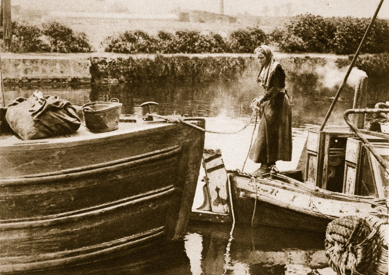 Una mujer asegurando la popa de su barcaza, Londres de English Photographer