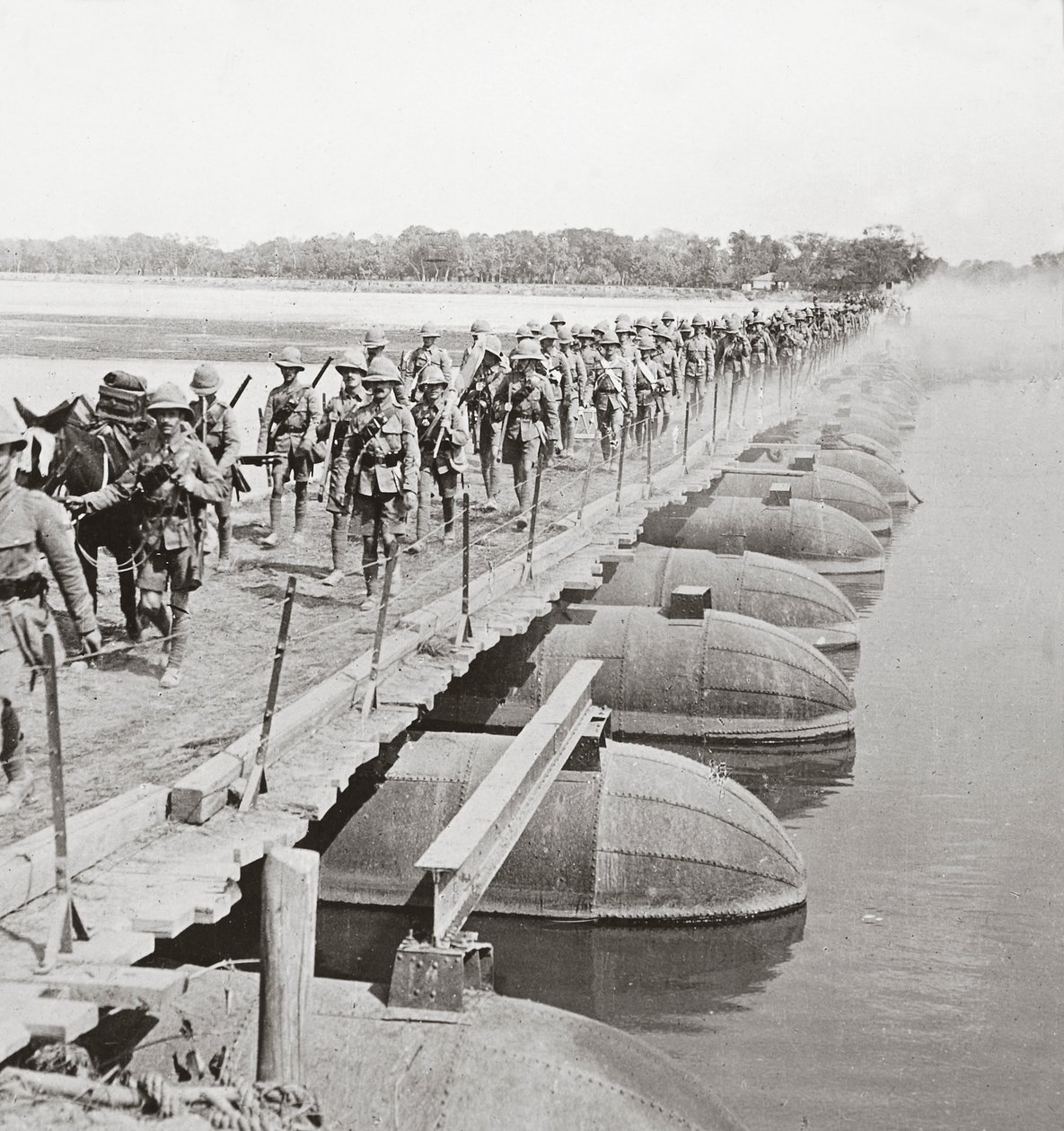 Sección de ametralladoras e infantería cruzando un río inundado por un puente de pontones de English Photographer