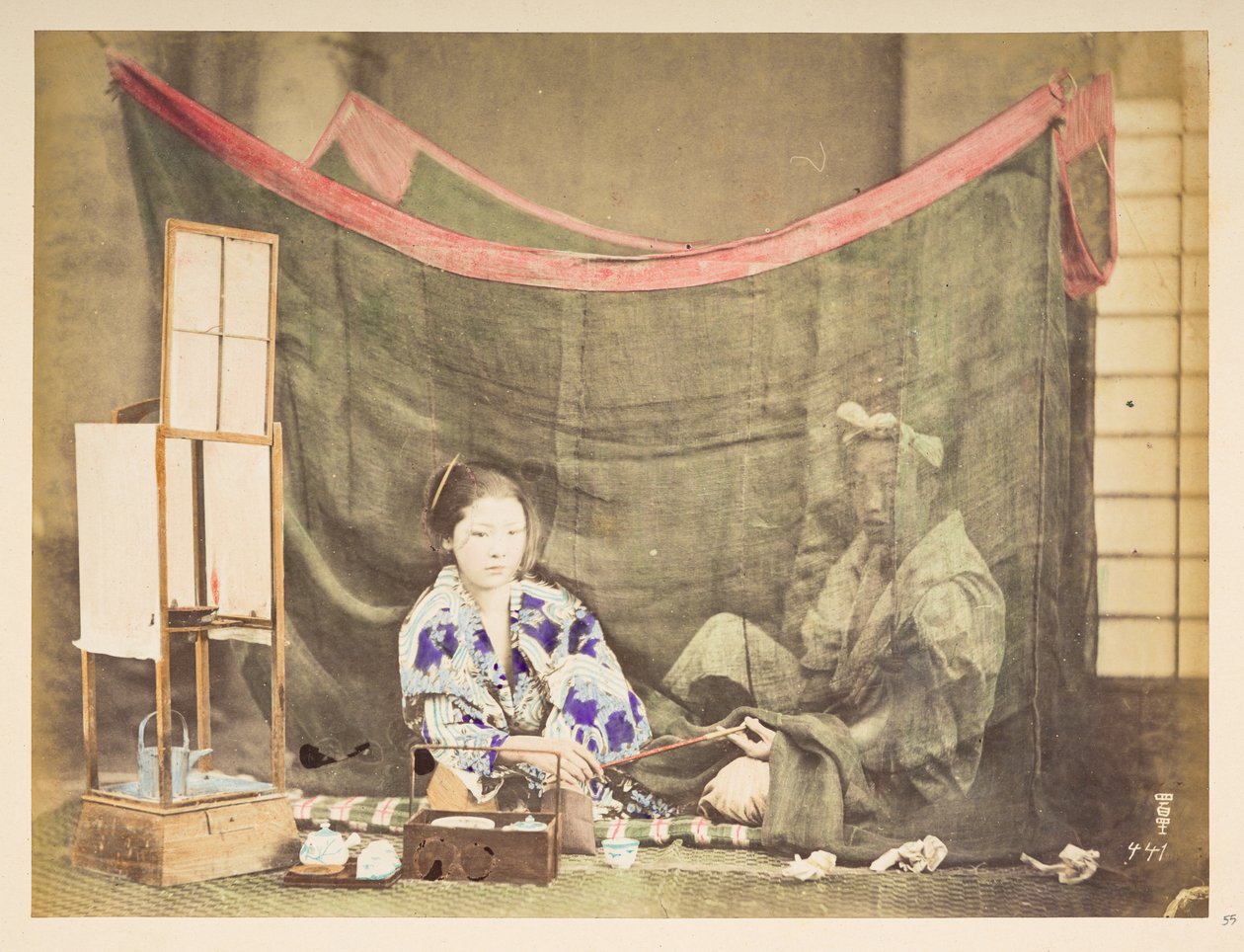 pareja japonesa en su tiempo libre, Cuadro de estudio de una joven japonesa, sentada con un impedimento para preparar té a su alrededor, entregando una pipa a una figura masculina que se sienta detrás de ella, protegida por un mosquitero de lino,   Fotógra de English Photographer