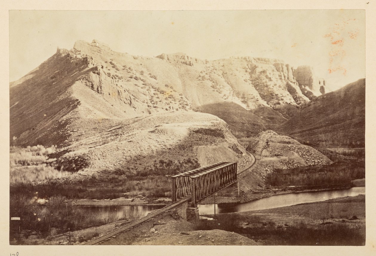 Vistas sobre el Ferrocarril del Pacífico, de la vía férrea que cruza un río en un puente de vigas, con montañas más allá de English Photographer