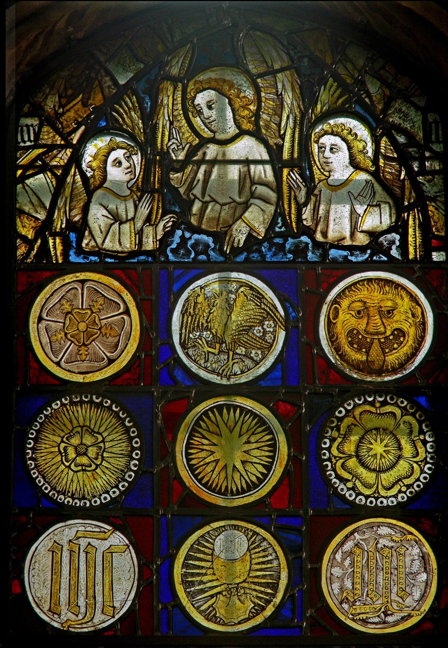 Un panel en la ventana este que representa ángeles sobre 9 medallones con resplandores solares, rosas, una cabeza de leopardo, un cáliz y monogramas de English School