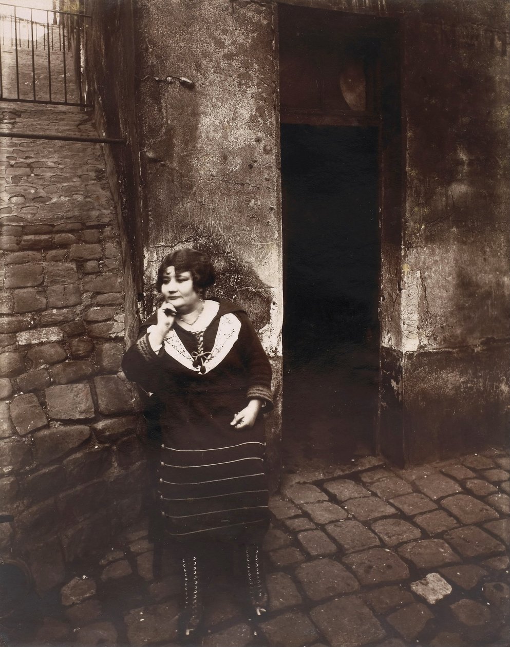 La Villette. Rue Asselin, prostituta esperando frente a su puerta de Eugène Atget