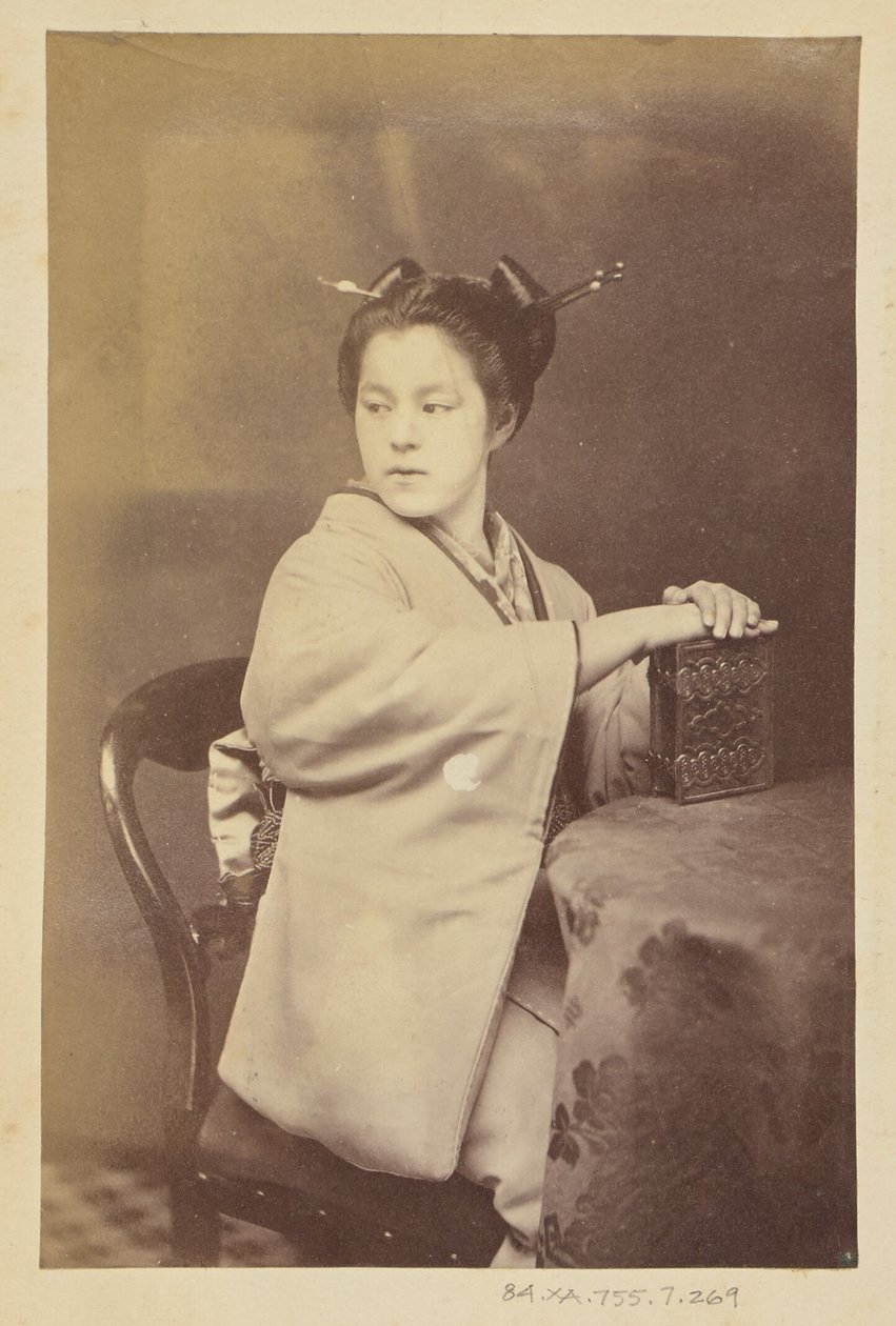 [Mujer japonesa sentada sosteniendo un álbum de cartes-de-visite en una mesa] de Felice Beato