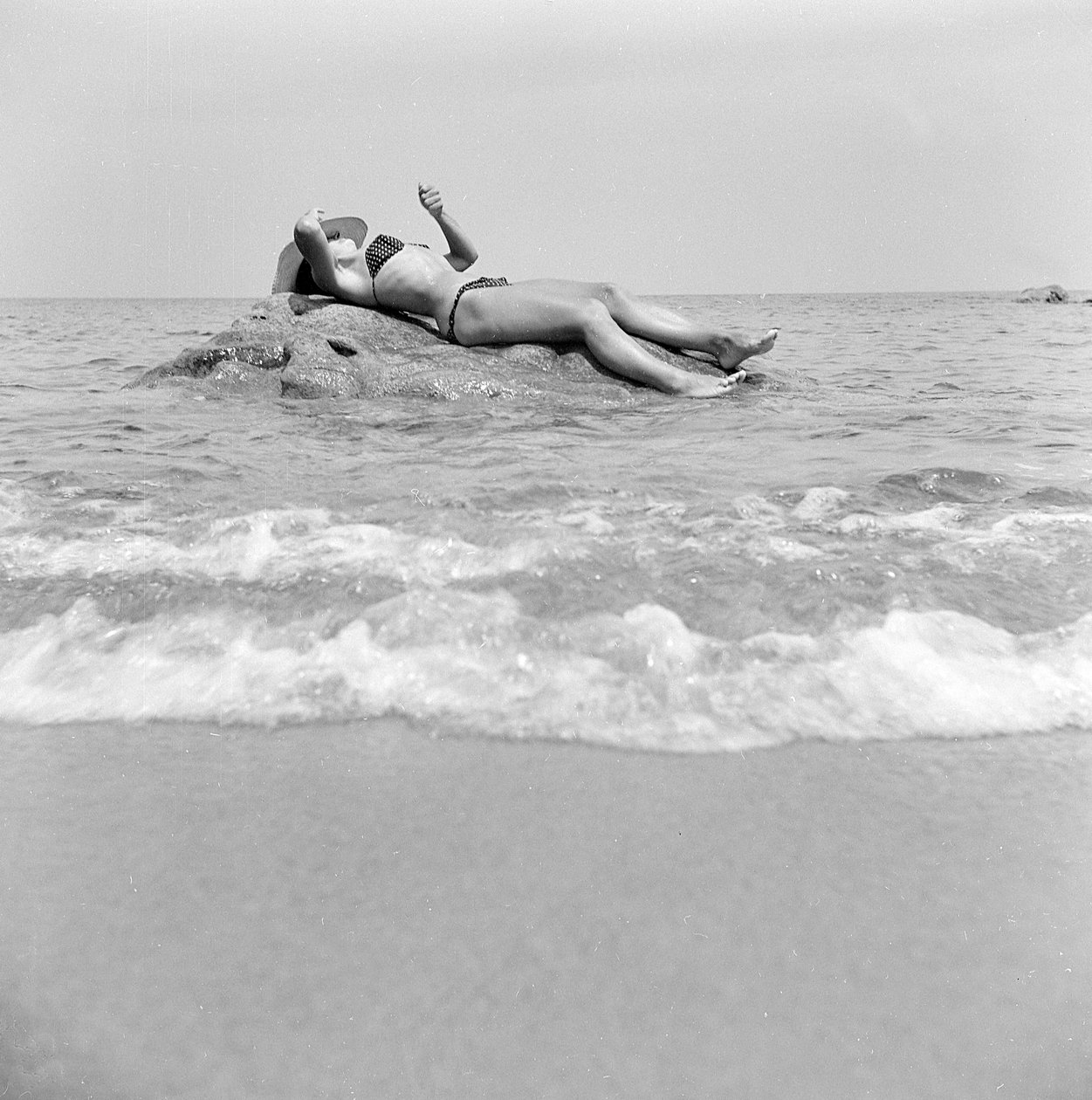 Chica tomando el sol en una roca en Cefalu de Fosco Maraini