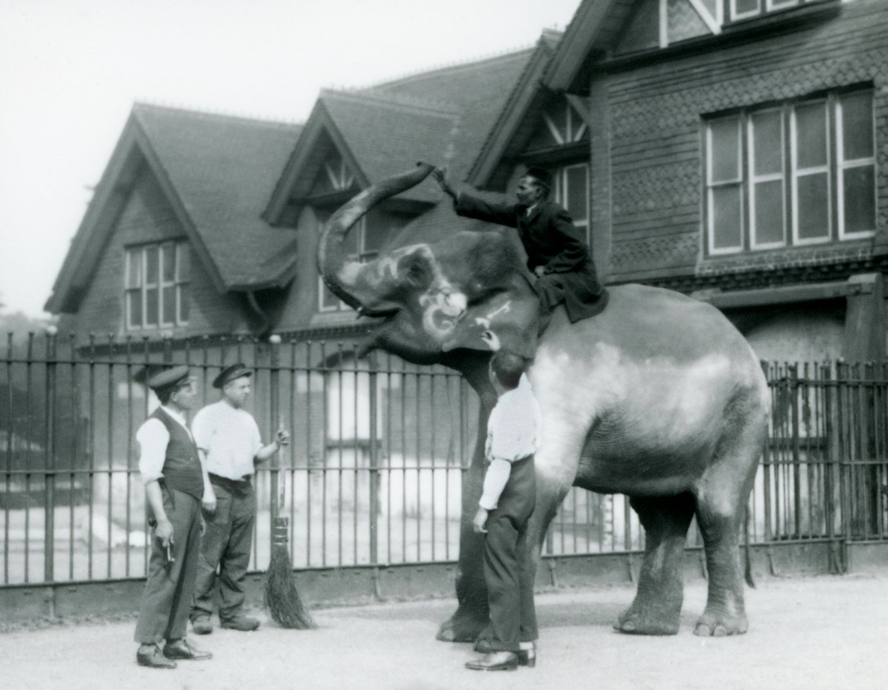 Un Elefante Indio decorado, con tres cuidadores y entrenador, fuera de la Casa del Elefante en el Zoológico de Londres en 1927 de Frederick William Bond