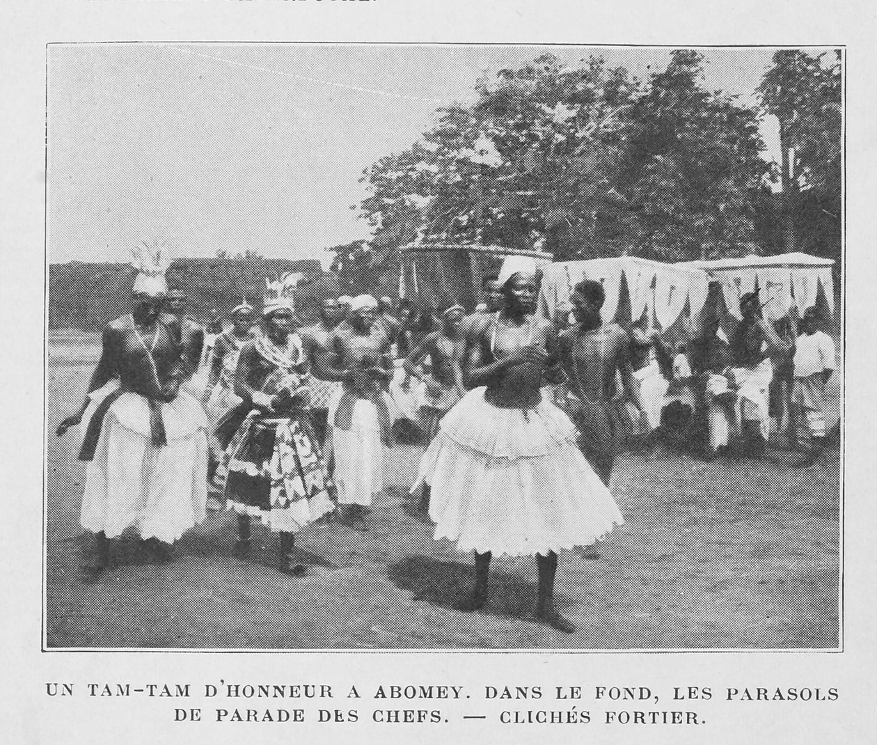 Un Tam-Tam de honor en Abomey con parasoles de los jefes en el fondo de French Photographer