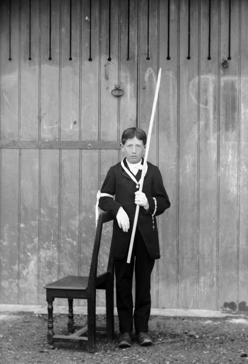 Primer comulgante, con traje blanco y guantes, con medallas, rosario, puño de encaje blanco y portando una vela muy larga, cerca de Bourmont en Haute-Marne, circa 1880. Fotografía. Colección Ducos de French Photographer