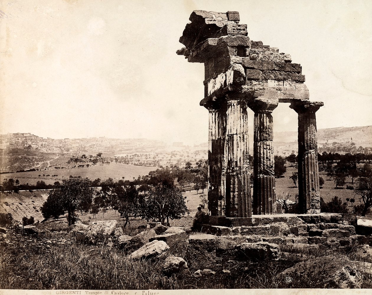Vista de las cuatro columnas restantes que sostienen un entablamento del Templo de Cástor y Pólux en el Valle dei Templi, Agrigento. Un panorama de la ciudad es visible al fondo de Giorgio Sommer