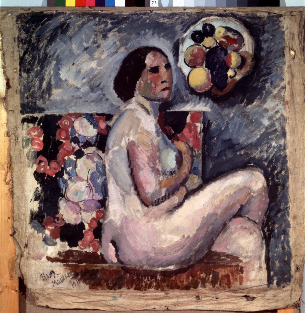 Akt. Retrato de una mujer desnuda, sentada con las piernas cruzadas, de perfil, haciendo un gesto de modestia. Detrás de ella, un cuadro de frutas y un sombrero decorado con frutas colgados en la pared. Pintura de Ilya Ivanovich Mashkov (Ilia Machkov, Matc de Ilya Ivanovich Mashkov