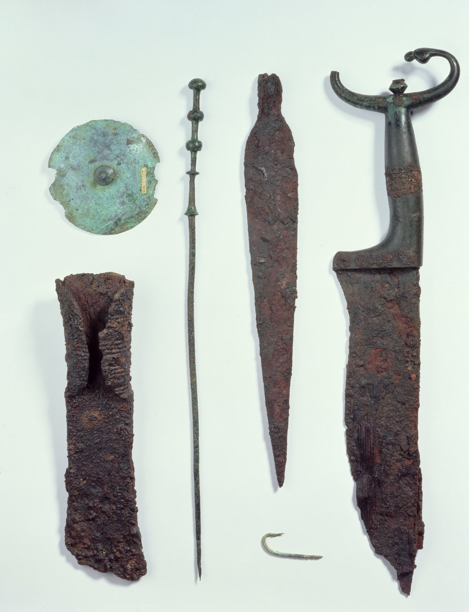 De arriba a abajo: cuchillo, punta de lanza, anzuelo, pinza de ropa, disco de cinturón y hacha, todos encontrados en tumbas masculinas en Hallstatt, Edad de Hierro de Iron Age