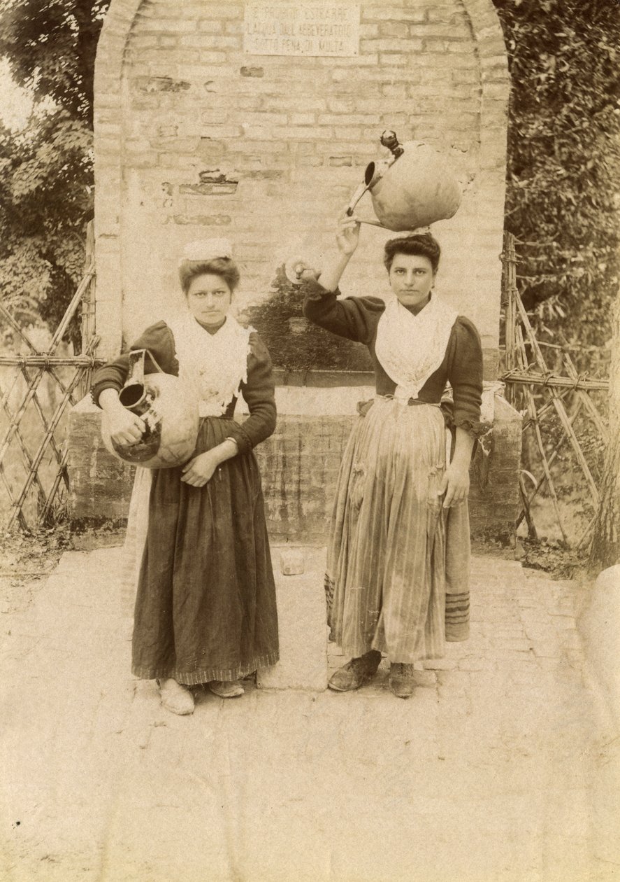 Dos mujeres jóvenes con trajes tradicionales y jarras de terracota cerca de un pozo, Las Marcas, Italia, hacia 1910. de Italian Photographer