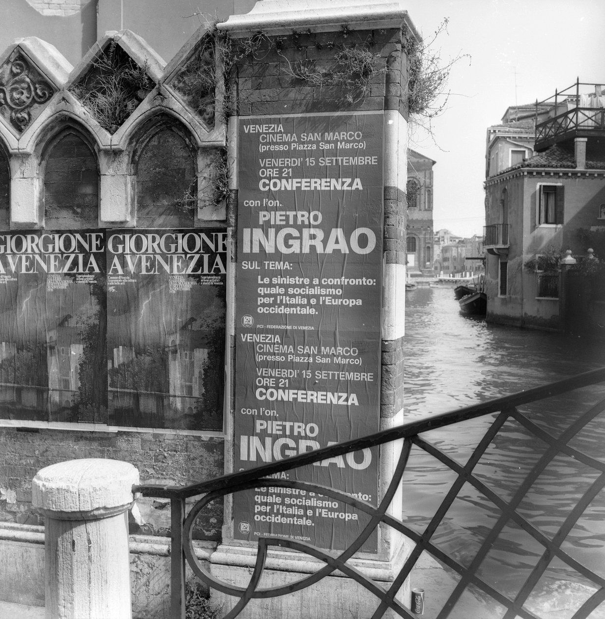Vista de un canal en Venecia con carteles que anuncian una exposición de Giorgione y un manifiesto político en primer plano de Italian Photographer